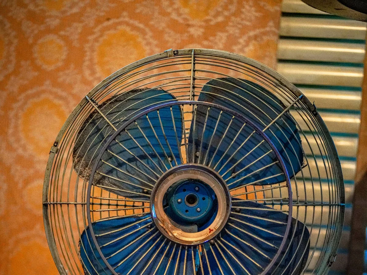 A quiet small fan moving air beside a summer bed