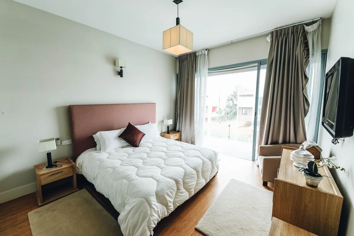A window shade and curtain overlapping the edges of a bedroom window
